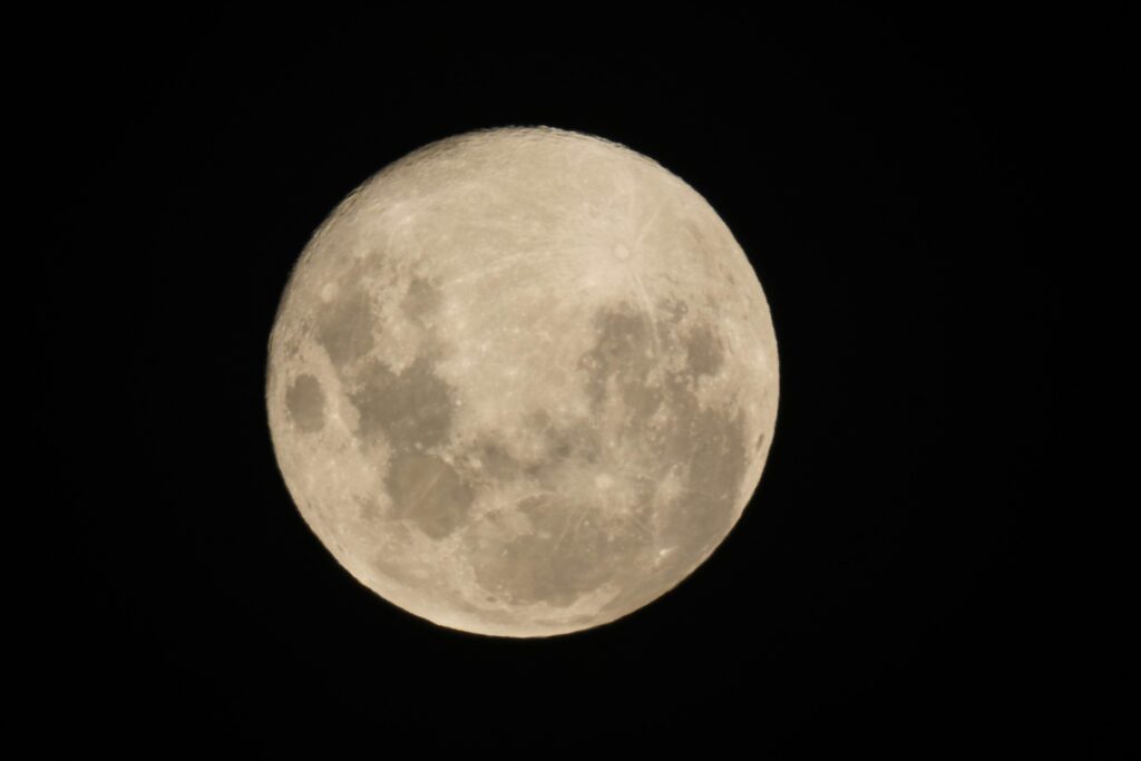 Detailed view of a full moon against a pitch-black night sky.