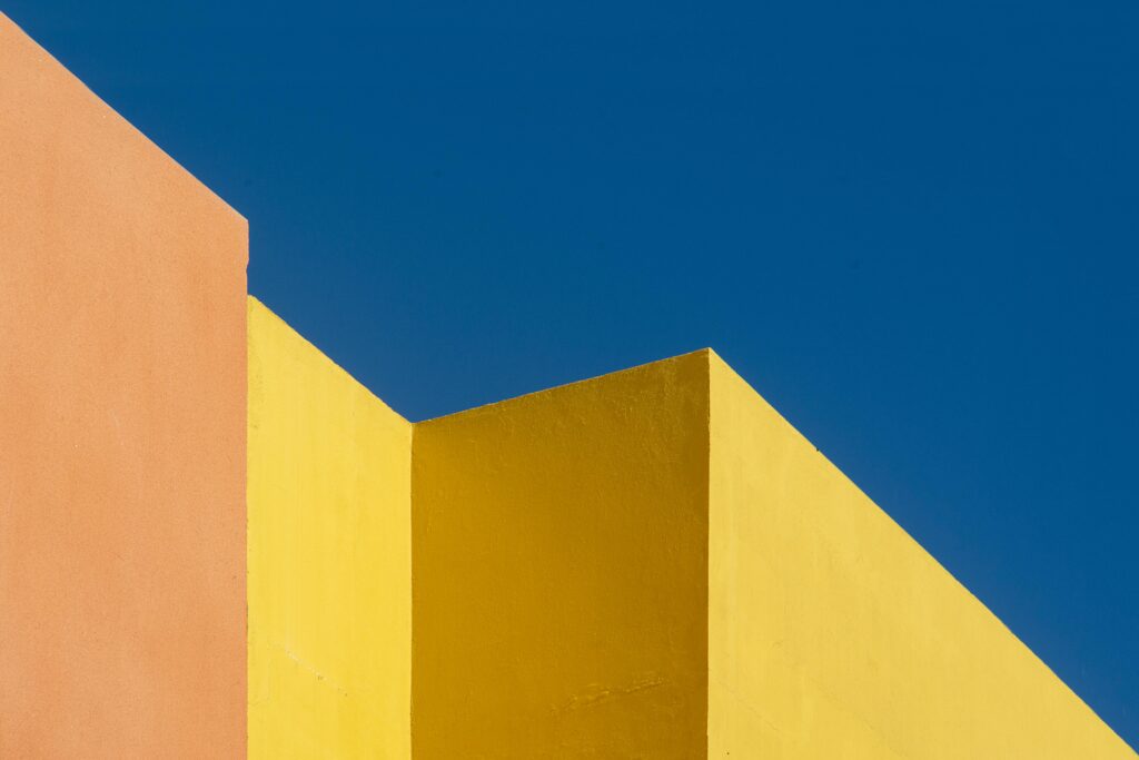 Colorful abstract architecture with geometric wall shapes against a vivid blue sky.