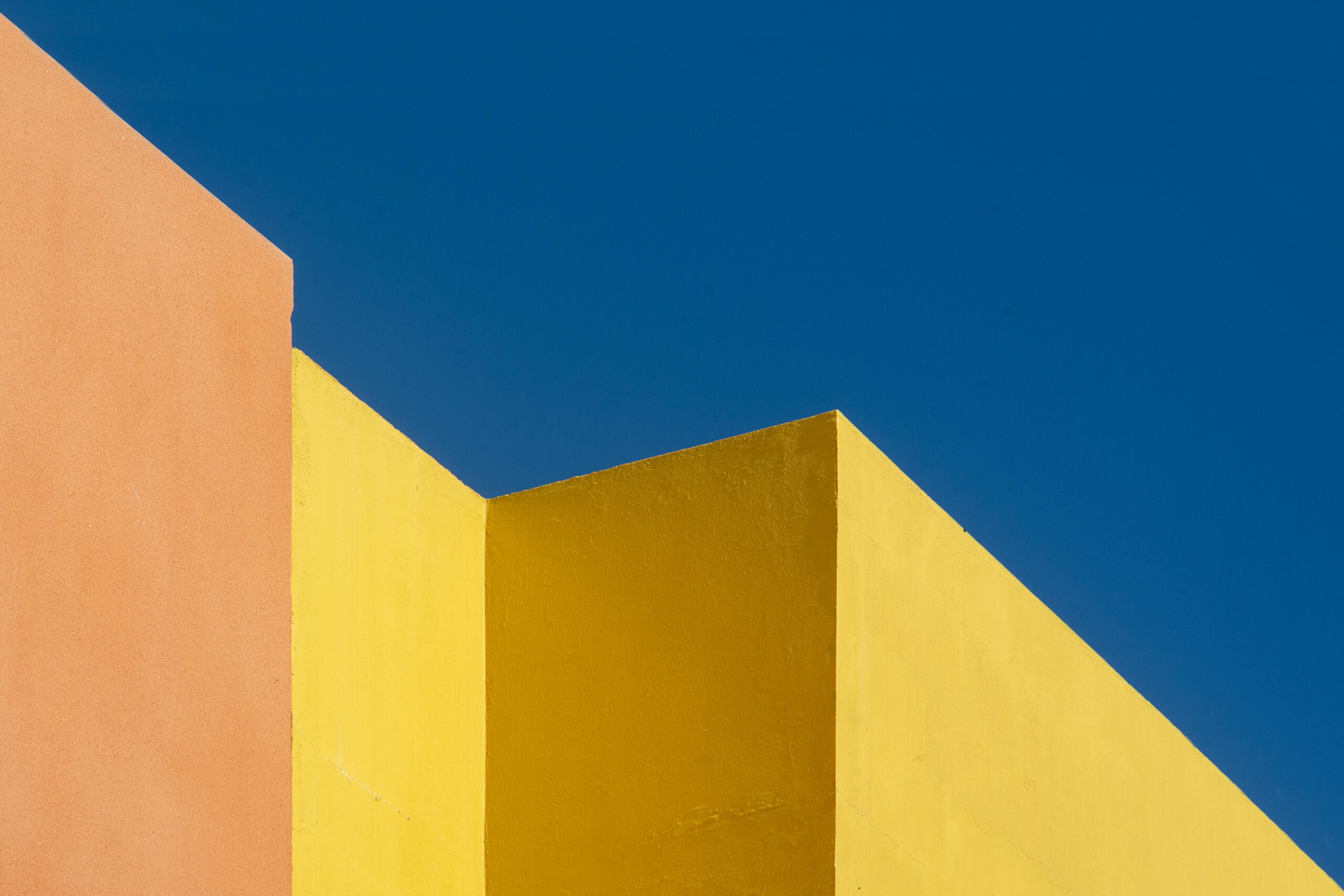 Colorful abstract architecture with geometric wall shapes against a vivid blue sky.