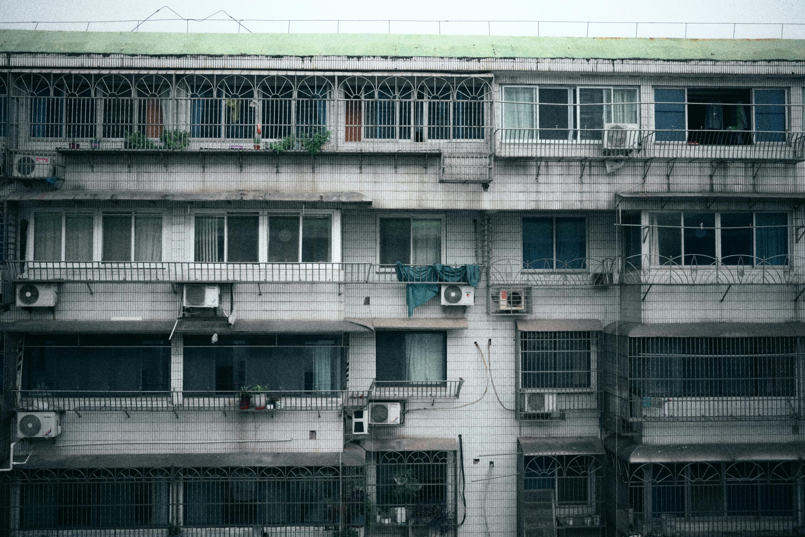 Facade of a multi-story apartment building with air conditioning units visible on each floor.