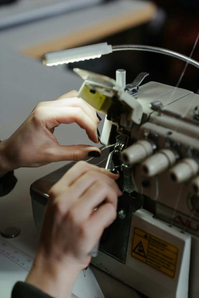 Hands adjusting a sewing machine, showcasing detailed needlework and craftsmanship.