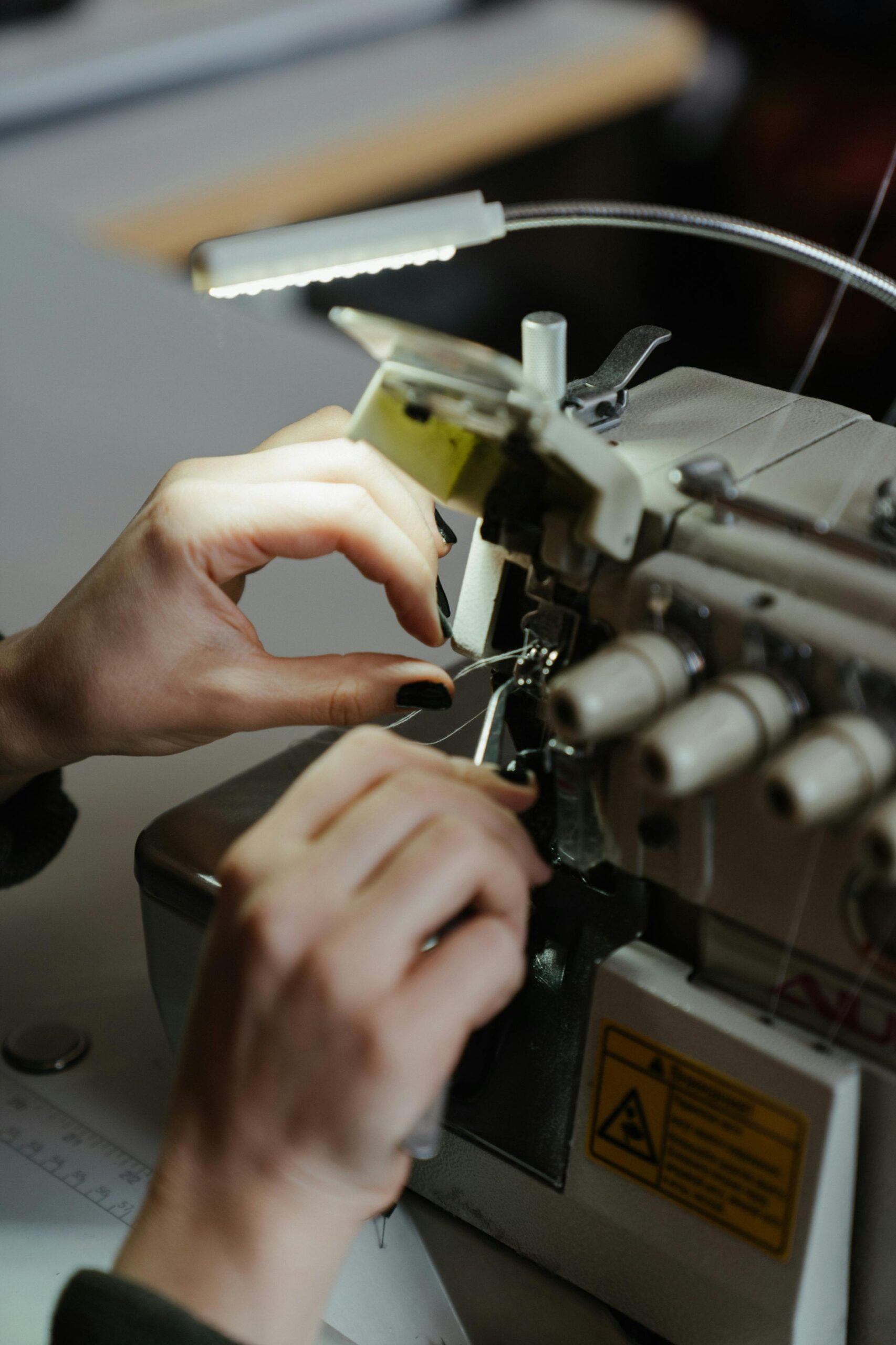 Hands adjusting a sewing machine, showcasing detailed needlework and craftsmanship.