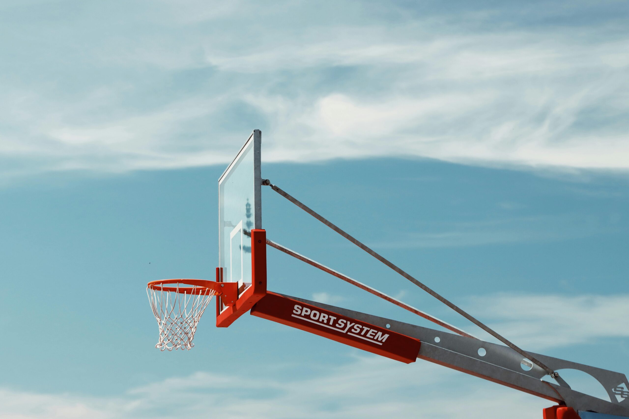 A basketball hoop with a transparent backboard set against a clear blue sky in Saulkrasti, Latvia.