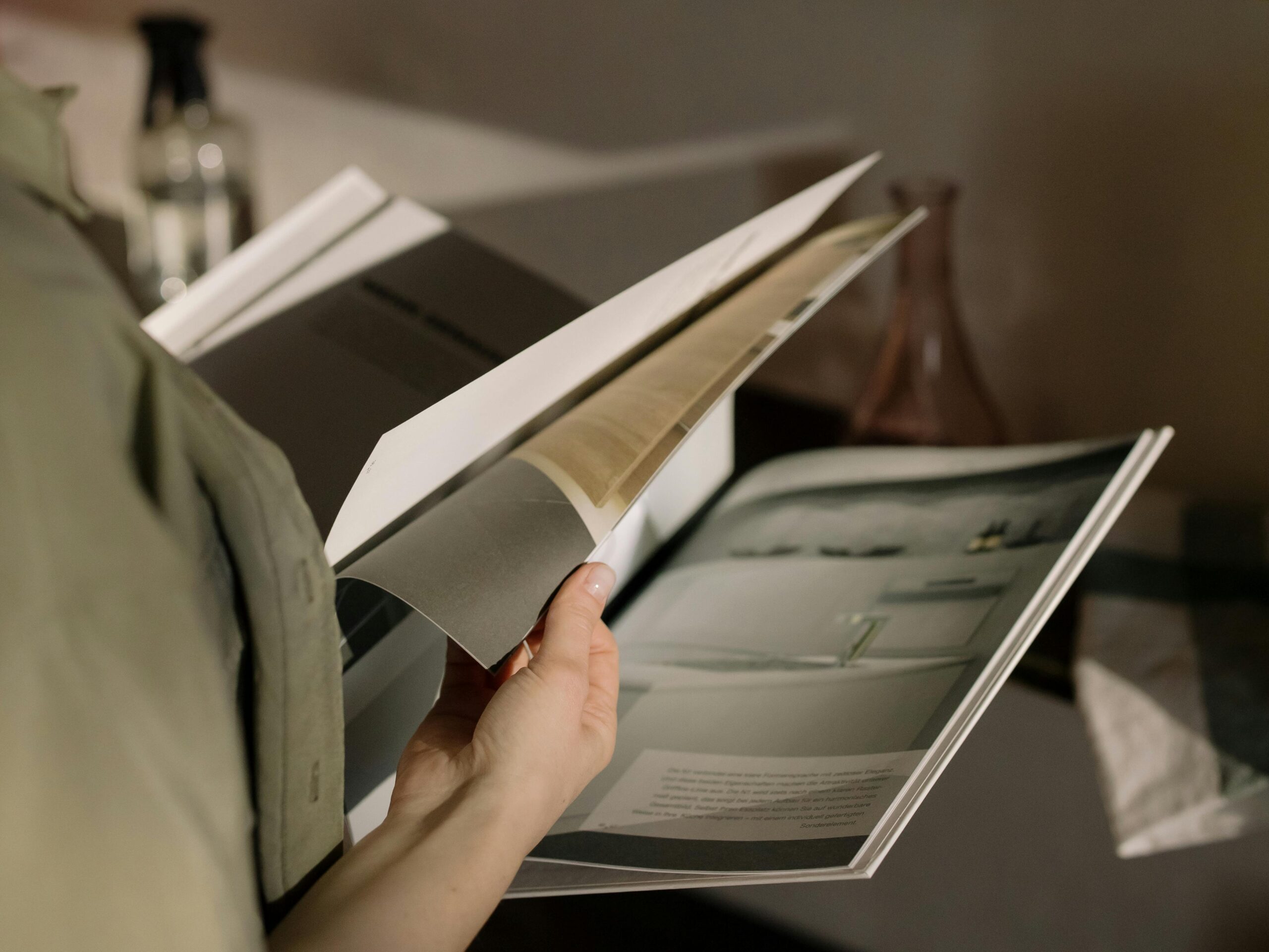 Close-up of a person flipping through a magazine indoors with soft lighting.