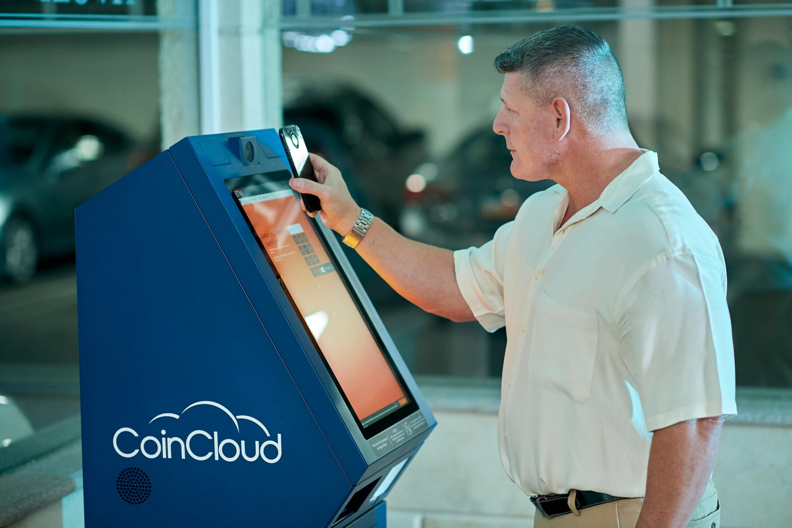 A mature man uses a CoinCloud Bitcoin ATM indoors, showcasing modern financial technology.