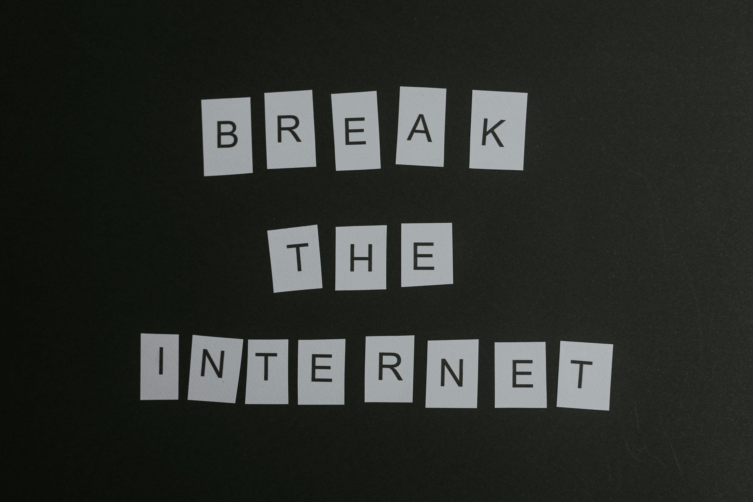 Conceptual flat lay of 'Break the Internet' message with white letters on a black background.