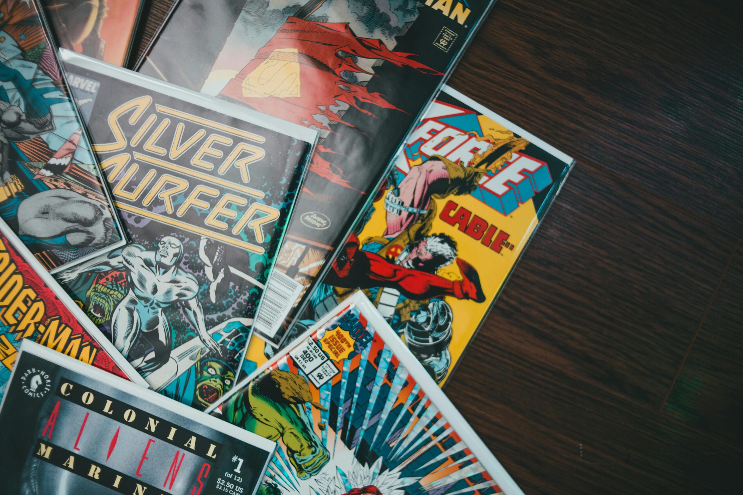 A vibrant assortment of classic comic book covers displayed flat on a wooden surface.