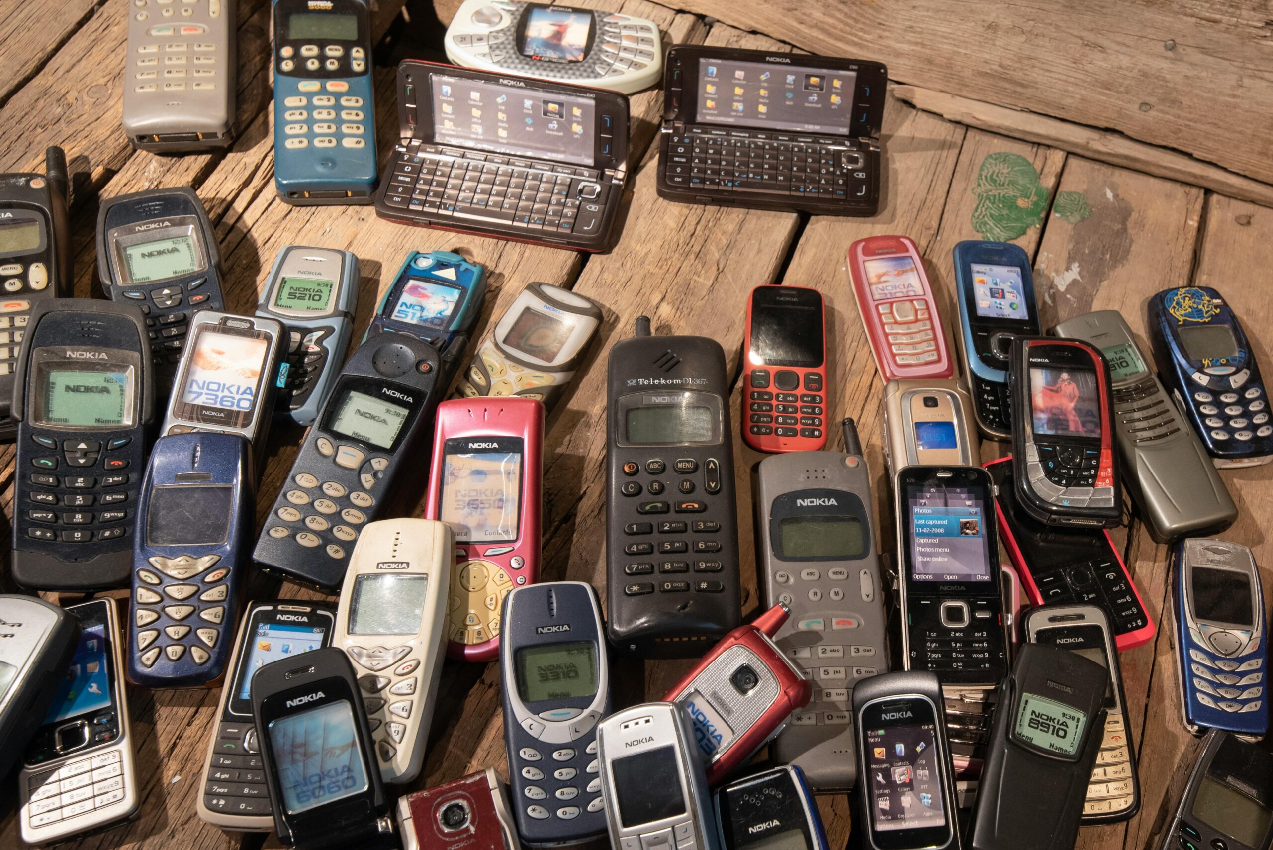 An assortment of retro mobile phones displayed on a rustic wooden surface, showcasing nostalgia.