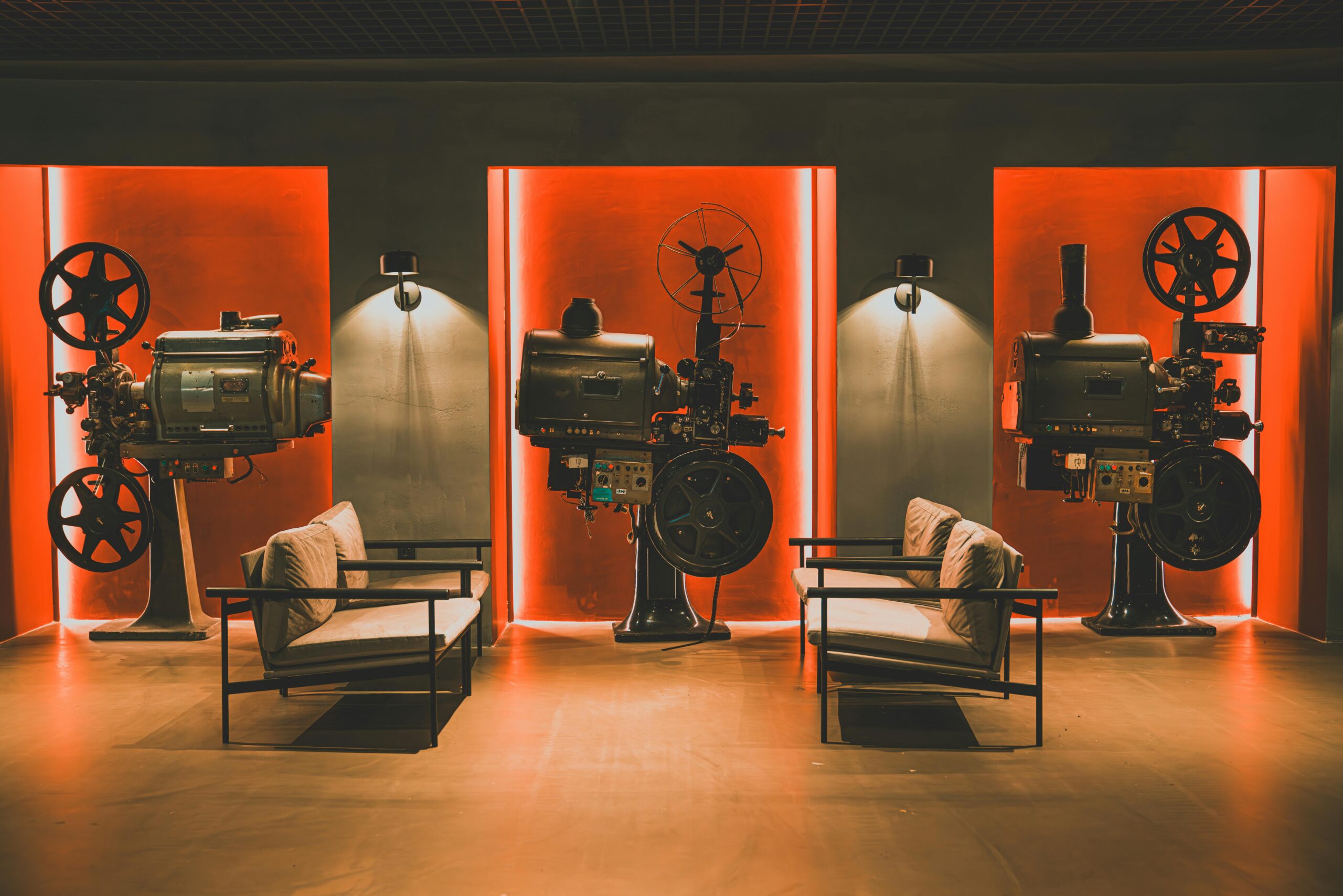 A cozy retro cinema room showcasing vintage film projectors and comfortable seating.