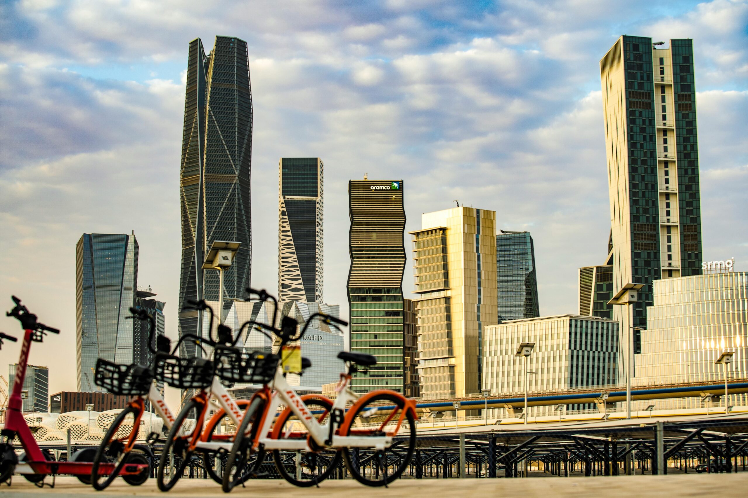 View of Riyadh skyline showcasing modern architecture against a vibrant sky with bicycles in the foreground.